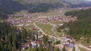 Hava aracı tavaları ve ileri hareket, Mestia ve Ushguli yakınlarındaki Svaneti vadisini gösteriyor. Metal çatılı küçük evler, asfaltsız yollar, çayırlar, kozalaklı ormanlar ve dağ sırtlarında kar..