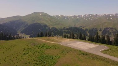 Mestia ve Ushguli yakınlarındaki Svaneti 'deki Gürcistan vadisinin hava manzarası. İnsansız hava aracı otlakları, kozalaklı ormanları, karla kaplı tepeleri, köyü, yolları, dereyi ve bir dağ helikopter pistini süpürüp geçiyor..