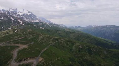 Hava aracı Mestia ve Ushguli yakınlarındaki Büyük Kafkasya üzerinde süzülüyor. Kar tepeleri, yeşil çayırlar, yılansı toprak yollar, küçük binalar ve bulutlu yaz ışıklarını gösteriyor..