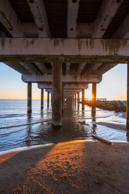 Yıpranmış beton iskele altındaki alçak açı, Baltık Denizi, Litvanya 'ya giden alg işaretli sütunları gösteriyor..