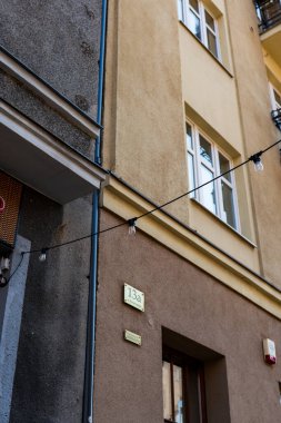 13A plaket, ahşap pencere, sicim lambaları, sıva ve beton, yumuşak gündüz hafif metal çıkıntıları olan eski bir Avrupa apartman cephesinin sokak manzarası..