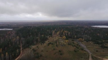 Dretunsky 'nin hava manzarası bir tepedeki harap sığınakları gösteriyor, iki göl, sonbahar huş ağacı ve çam ağacı, toprak yollar, yalnız bir araç, küçük figürler ve çapraz çizgiler..