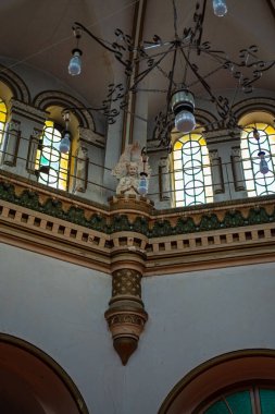 Lukiskes Cezaevi 'nin loş ışıklı Vilnius şapeli köşesinde kubbeli, boyalı camlar, yeşil frizler ve işlenmiş demir avizesi ve soyulmuş alçılı küçük bir heykel görülüyor..