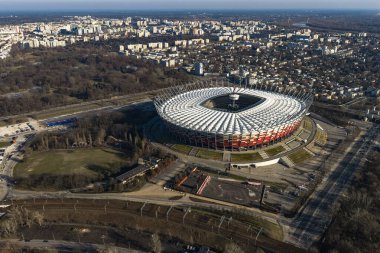 Varşova 'daki PGE Narodowy' nin beyaz çatılı, kırmızı ve beyaz cepheli Vistula nehri parkları ve demiryolu hatları, Praga bölgeleri ve apartmanları, öğleden sonra ışığı altında..