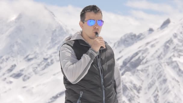 Giovane uomo con gli occhiali, fumare la sigaretta elettronica su uno sfondo montagne — Video Stock