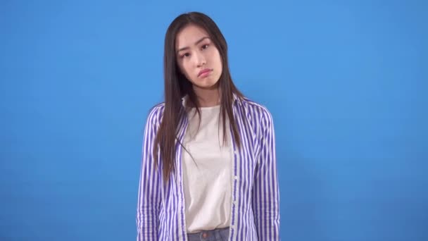 셔츠를 입고 푸른 배경에 머리를 부정적으로 흔들고 있는 젊은 이시아 여자 — 비디오