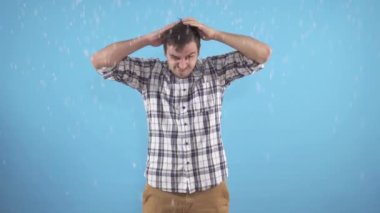 Adam kafasını mavi arka planda kepek problemine sürtüyor.