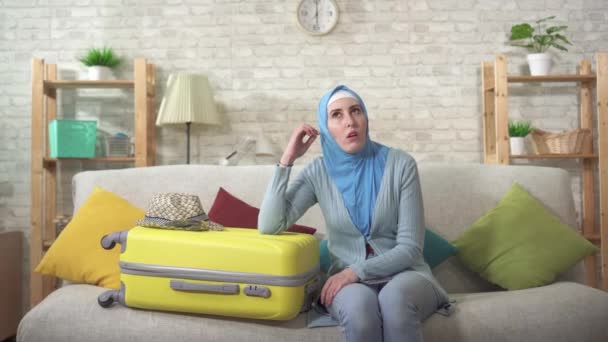 Mulher muçulmana descontente está sentado no sofá esperando com o telefone na mão — Vídeo de Stock