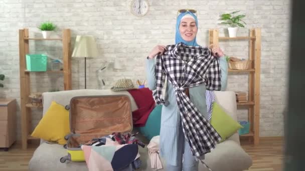 Jovem mulher muçulmana alegre está fazendo uma mala para férias — Vídeo de Stock