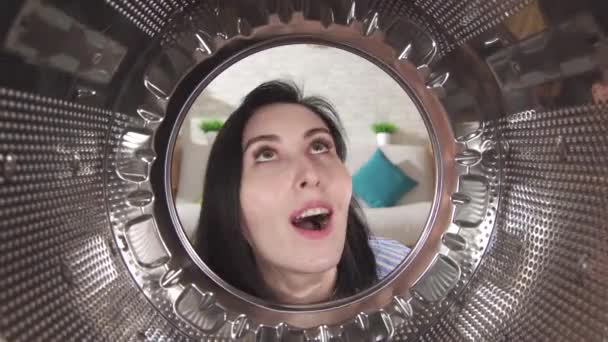 Ung kvinne undersøker med glede trommelen i en vaskemaskin – stockvideo
