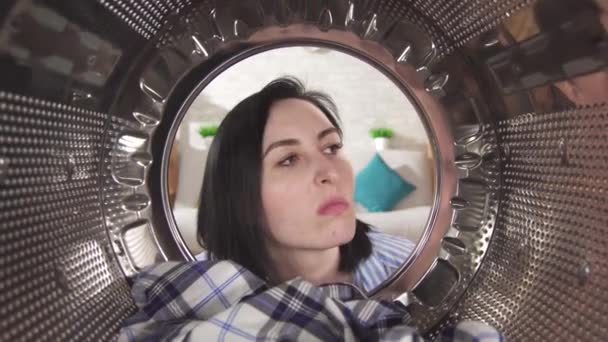 Młoda kobieta wyjmuje pralnię i czuje nieprzyjemny zapach z pralki. — Wideo stockowe