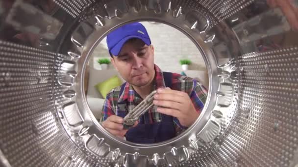 Tukang reparasi di sebelah mesin cuci memegang elemen pemanas rusak — Stok Video