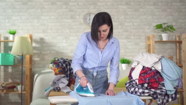 Young woman is engaged in Ironing and burns her finger — Stock Video