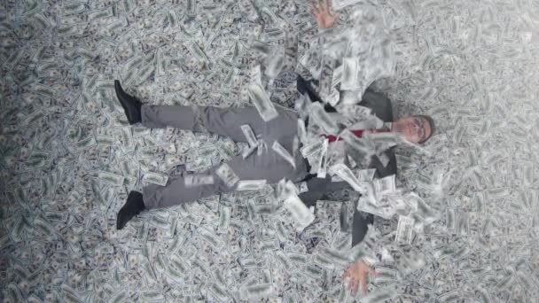 Веселый бизнесмен в ложь на фоне банкнот вид сверху медленный мо — стоковое видео