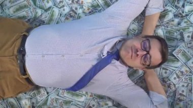 dikey video ekran portresi iş kıyafetleri içinde tatmin olmuş erkek işadamı banknotlara uzanır