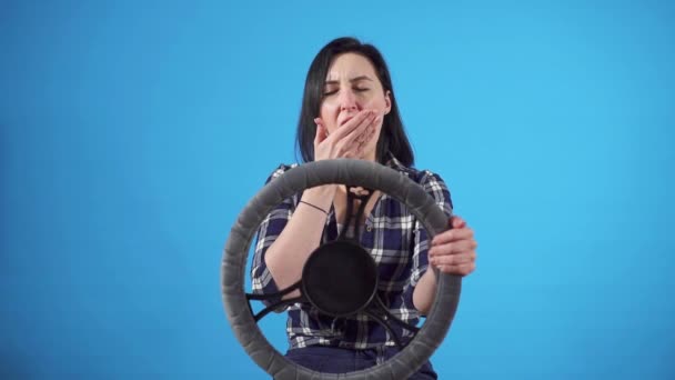 Портрет сонная женщина водитель зевает на руль, на синем фоне изолировать — стоковое видео