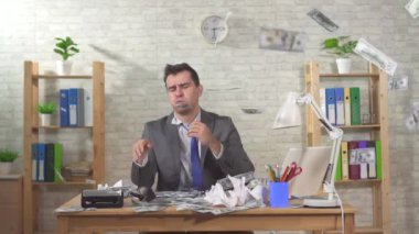 Hüsrana uğramış işadamı ofiste oturuyor ve banknotlar üzerine düşüyor, ağır çekimde.