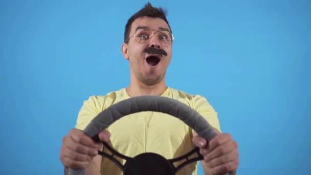 Expresivo hombre con un bigote detrás del volante sobre un fondo azul lento mo, aislar — Vídeos de Stock