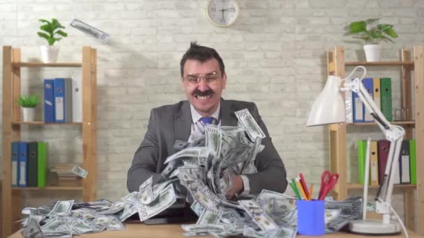 Expresivo hombre de negocios con una pila de dólares se sienta en una mesa en la oficina de mo lento — Vídeo de stock