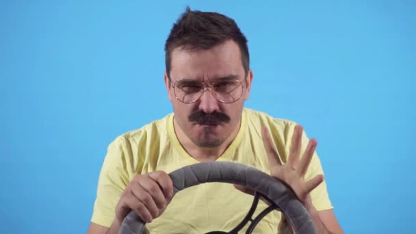 Koncentrált férfi bajusszal a volán mögött egy kék háttér lassú mo, izolálni — Stock videók