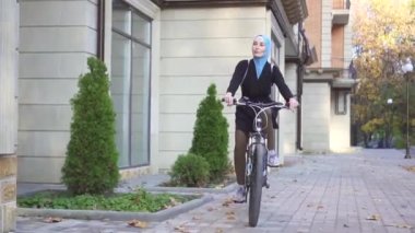tesettürlü güzel müslüman kadın şehirde bisiklet sürüyor.