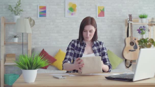 Jeune femme enveloppe un cadeau assis à la table lente mo — Video