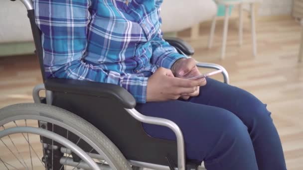 Mujer afroamericana discapacitada en silla de ruedas utiliza un teléfono inteligente — Vídeo de stock