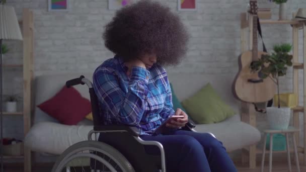 Smutný a osamělý zdravotně postižený africký Američan žena s afro účes v invalidním vozíku sedí sám — Stock video