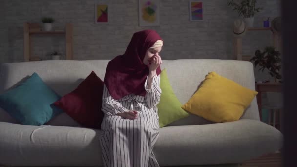 Junge Muslimin weint in Depressionen auf der Couch im Wohnzimmer — Stockvideo