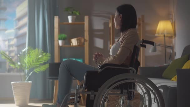 Retrato de una mujer discapacitada solitaria en un apartamento en un día soleado mirando por la ventana — Vídeos de Stock