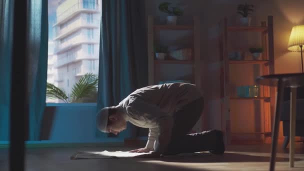 Porträt eines muslimischen Mannes mittleren Alters in traditioneller muslimischer Gebetsmütze, der in seinem Haus betet — Stockvideo