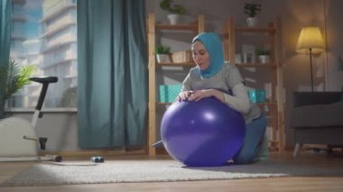Spor müslim kadın evde jimnastik topuyla spor egzersizleri yapıyor.