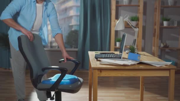 Man office worker or freelancer puts a seat cushion pillow for office chair — Stock Video
