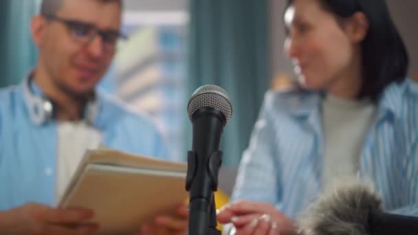 Hombre con gafas y una mujer grabar una entrevista podcast, micrófono de cerca — Vídeo de stock