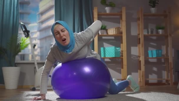 Portrait femme musulmane sur une blessure au ballon de fitness et mal au dos — Video
