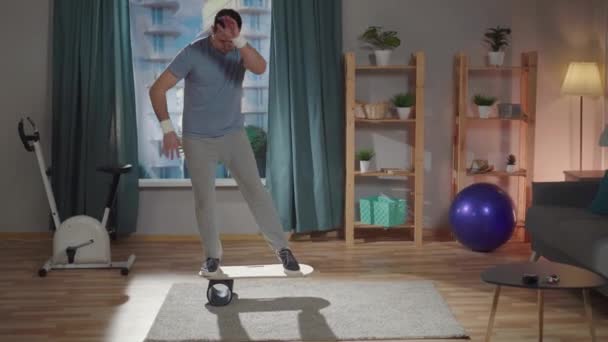 En mann trener på et balansebrett og faller – stockvideo
