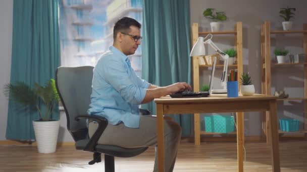 Um homem um trabalhador de escritório ou freelancer sentado em uma cadeira de escritório desconfortável se sente desconfortável — Vídeo de Stock