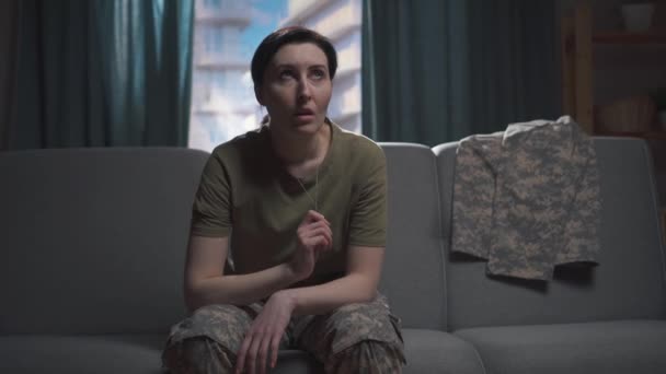 Junge Militärfrau sitzt auf dem Sofa und bedeckt ihr Gesicht mit den Händen — Stockvideo