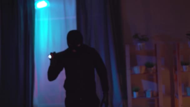 Портрет грабителя в балаклаве с фонариком в квартире — стоковое видео