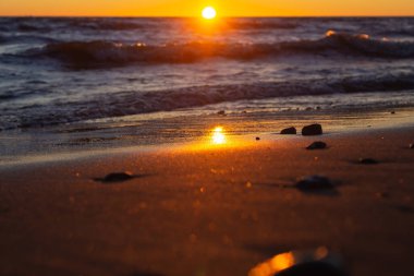 Akşamları kumsalda ıslak kum. Denizin üzerinde altın gün batımı