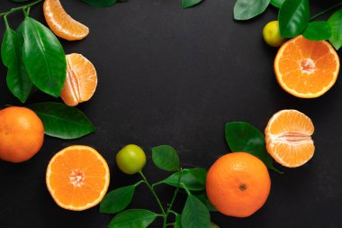 Siyah arka planda yaprakları olan mandalina ya da mandalina. Kopyalama alanı olan üst görünüm.