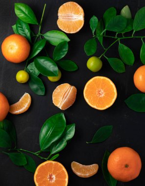 Siyah arka planda yaprakları olan mandalina ya da mandalina. Kopyalama alanı olan üst görünüm.