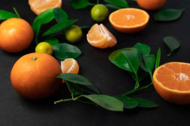 Siyah arka planda yaprakları olan mandalina ya da mandalina. Kopyalama alanı olan üst görünüm.