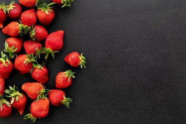 Siyah arka planda olgun çilekler, yaz meyveleri, üst manzara.