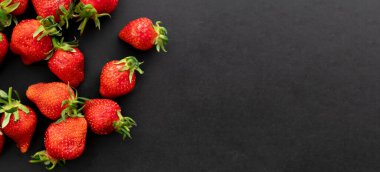 Siyah arka planda olgun çilekler, yaz meyveleri, üst manzara.