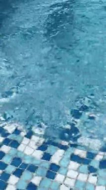 Açık mavi yüzme havuzu ve su yüzeyinde güneş ışığı yansımaları. Sakin dalgalar rahatlatıcı yaz havası yaratır, arka plan, seyahat ve tatil kavramları için mükemmeldir..