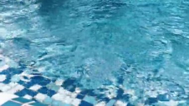 Açık mavi yüzme havuzu ve su yüzeyinde güneş ışığı yansımaları. Sakin dalgalar rahatlatıcı yaz havası yaratır, arka plan, seyahat ve tatil kavramları için mükemmeldir..