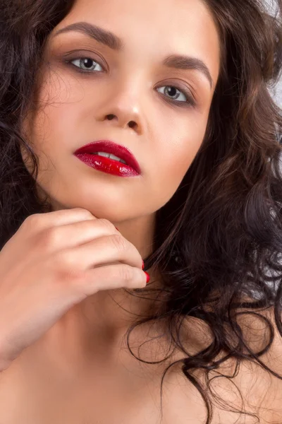 Beauty Model Woman with Long Brown Wavy Hair. Healthy Hair and Beautiful Professional Makeup. Red Lips and Smoky Eyes Make up. Gorgeous Glamour Lady Portrait. Red Manicure. Haircare, Skincare concept