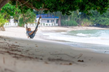 Tropik sahilde hamakta yatan genç kadın