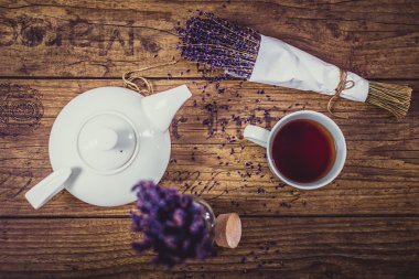 Bir avuç kuru kesim lavanta, fincan çay ve çaydanlık ahşap masa üzerinde. Üstten Görünüm.
